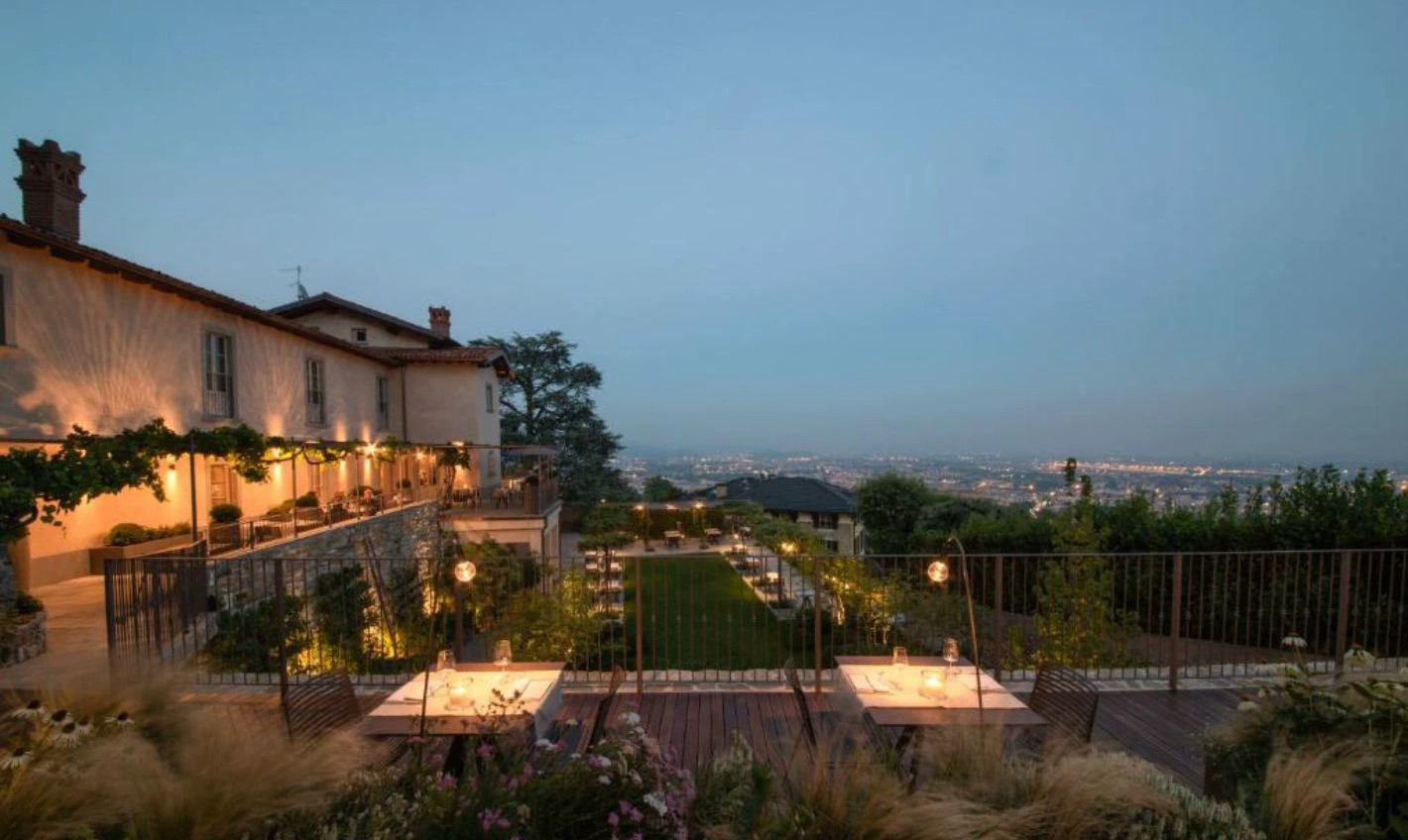 Relais San Vigilio al Castello at twilight, with terrace and panoramic view of Bergamo below