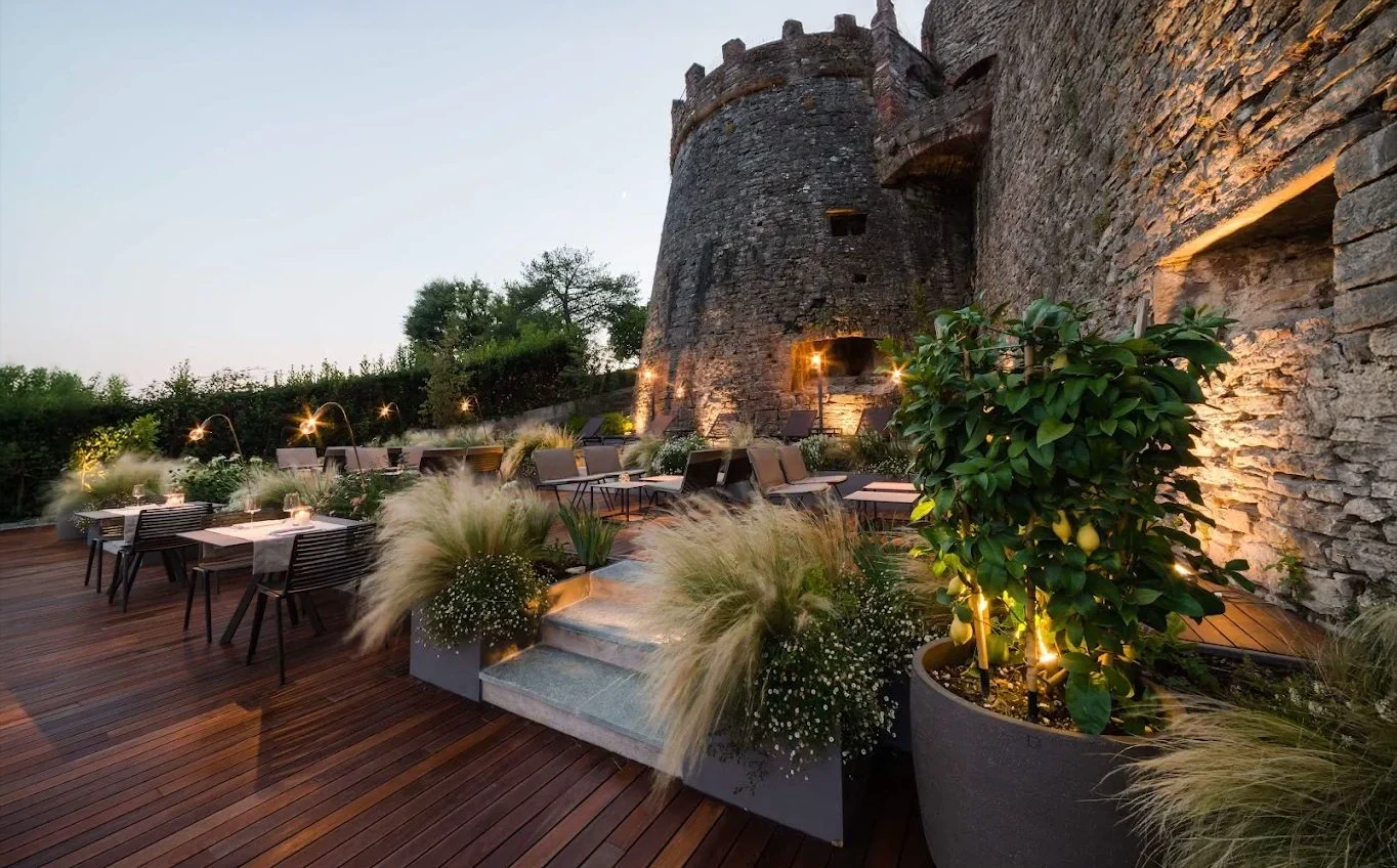 The castle tower at Relais San Vigilio, with terrace and candlelit tables at sunset